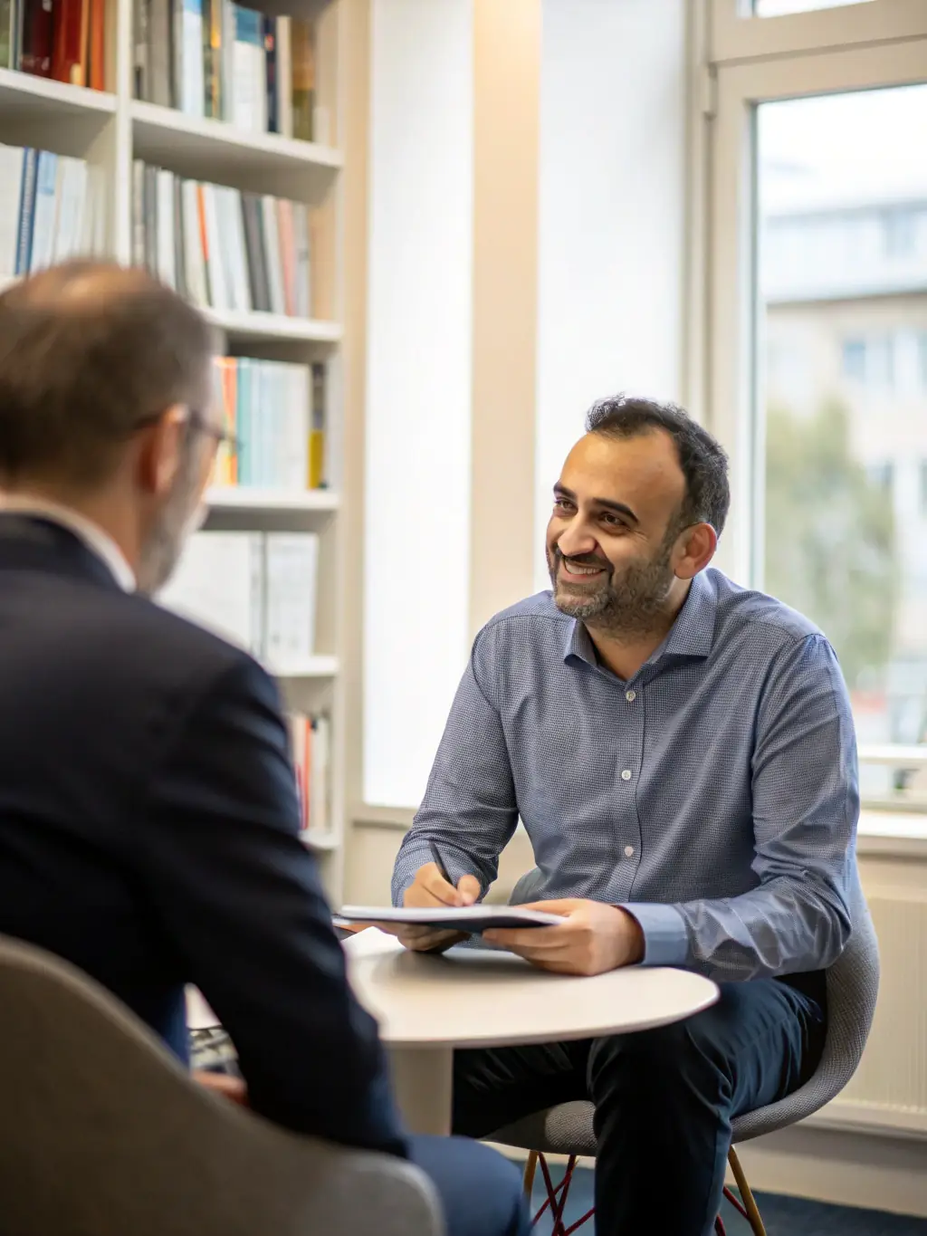 An image depicting a one-on-one coaching session in a modern office setting, with an Indian business leader receiving guidance from a coach.